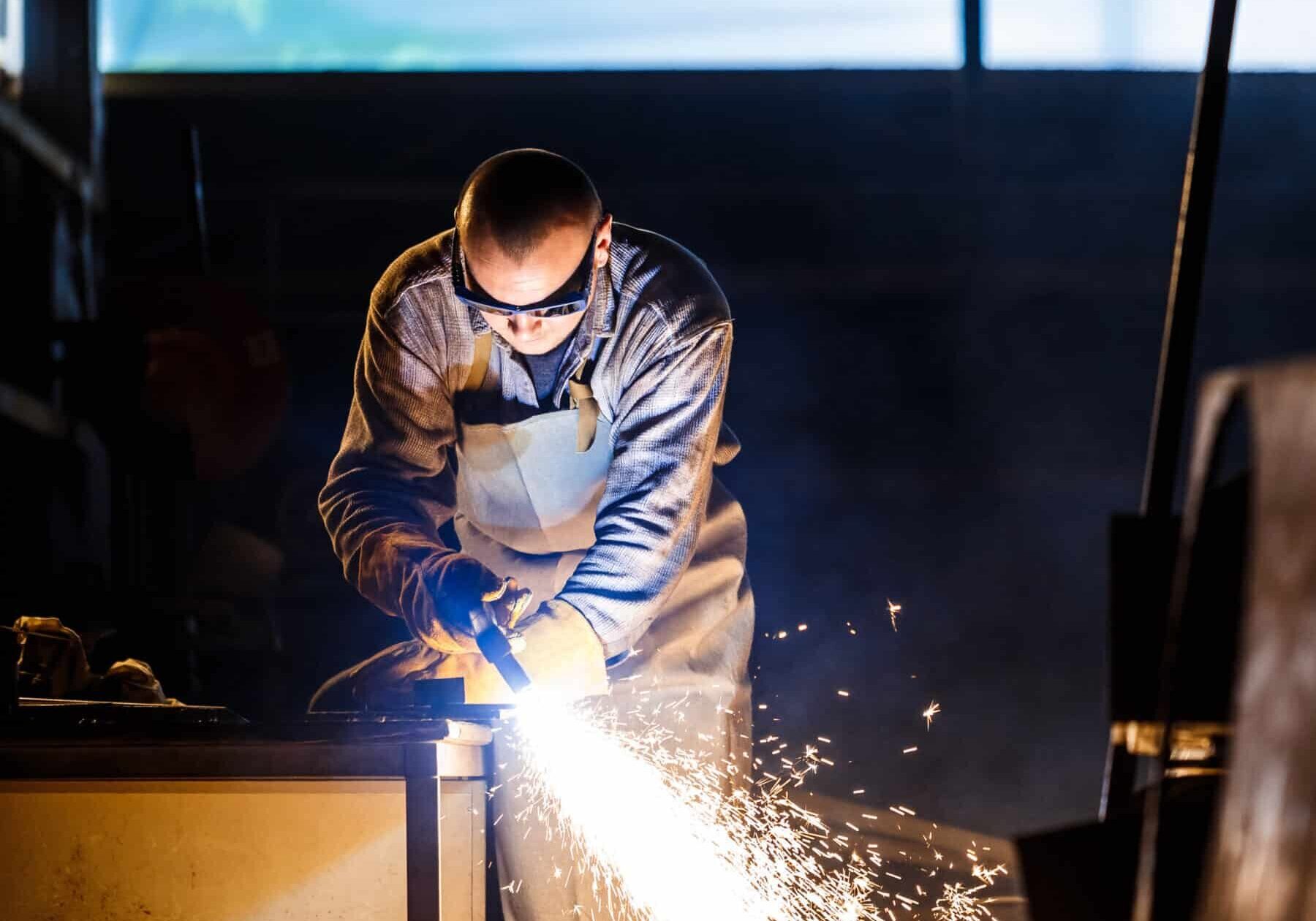 Worker cutting metal with plasma equipment on plant.